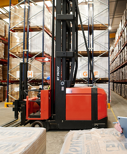 Elye Distribution warehouse with narrow‑aisle forklift operating between tall racking shelves, labelled inventory zones, and active fulfilment staff.