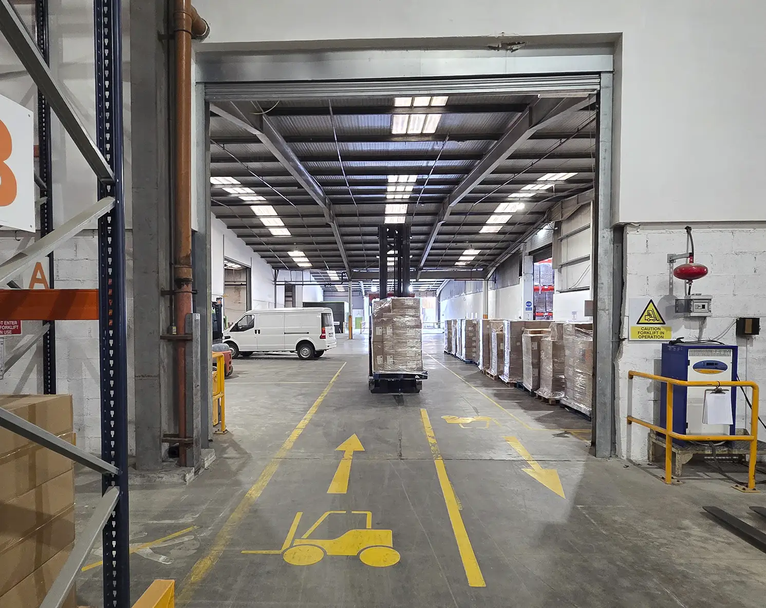 Elye Distribution – Forklift Operating on Marked Safety Route Forklift transporting goods along a marked safety route inside a warehouse.